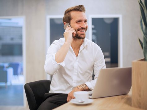 En glad affärsman som pratar i telefon med en kund på kontoret