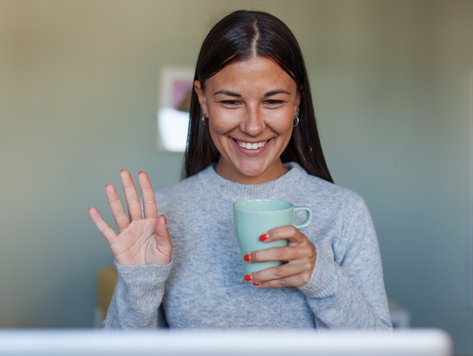 glad-ung-kvinna-som-hälsar-på-sina-kollegor-på-datorn