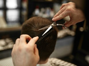 Frisör på frisörsalong klipper en killes hår.